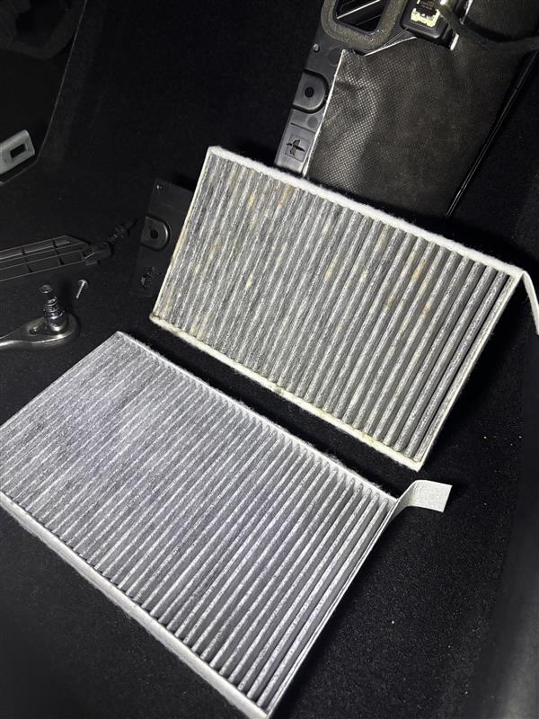 Used Tesla cabin air filter darkened with dust and debris next to a clean replacement activated carbon filter