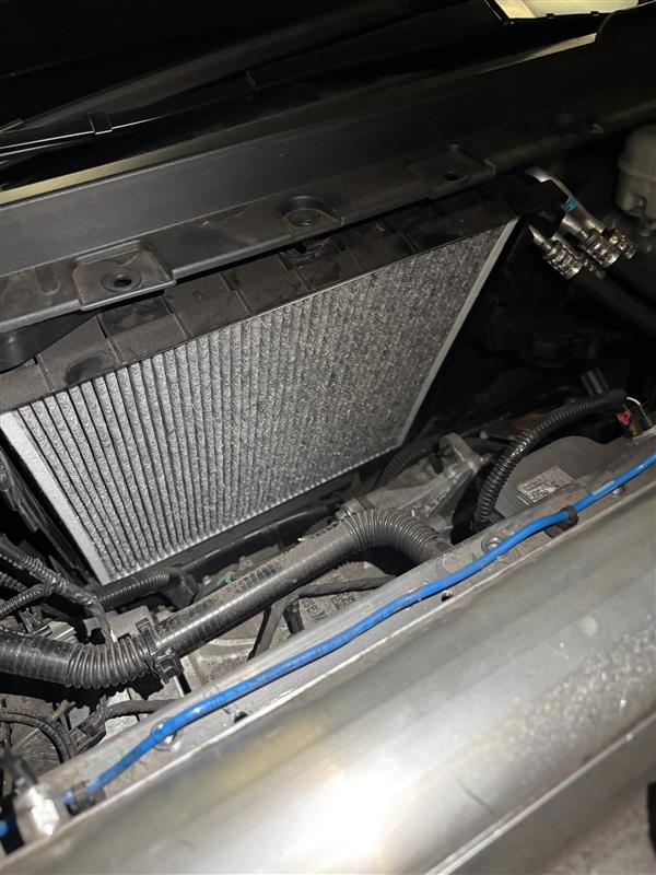 New Tesla cabin air filter seated in the HVAC housing behind the dashboard during a mobile replacement